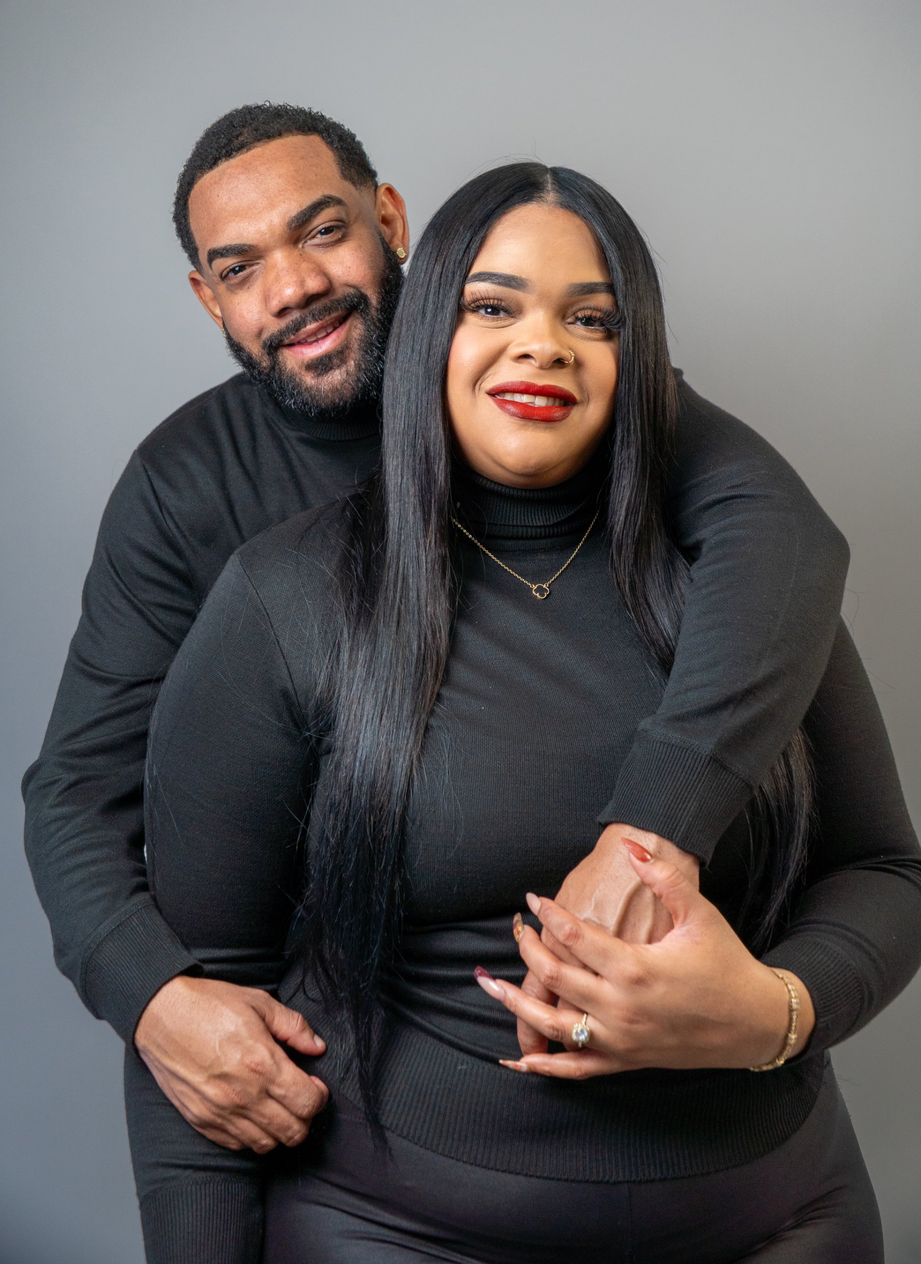 Couple in black, smiling in an embrace