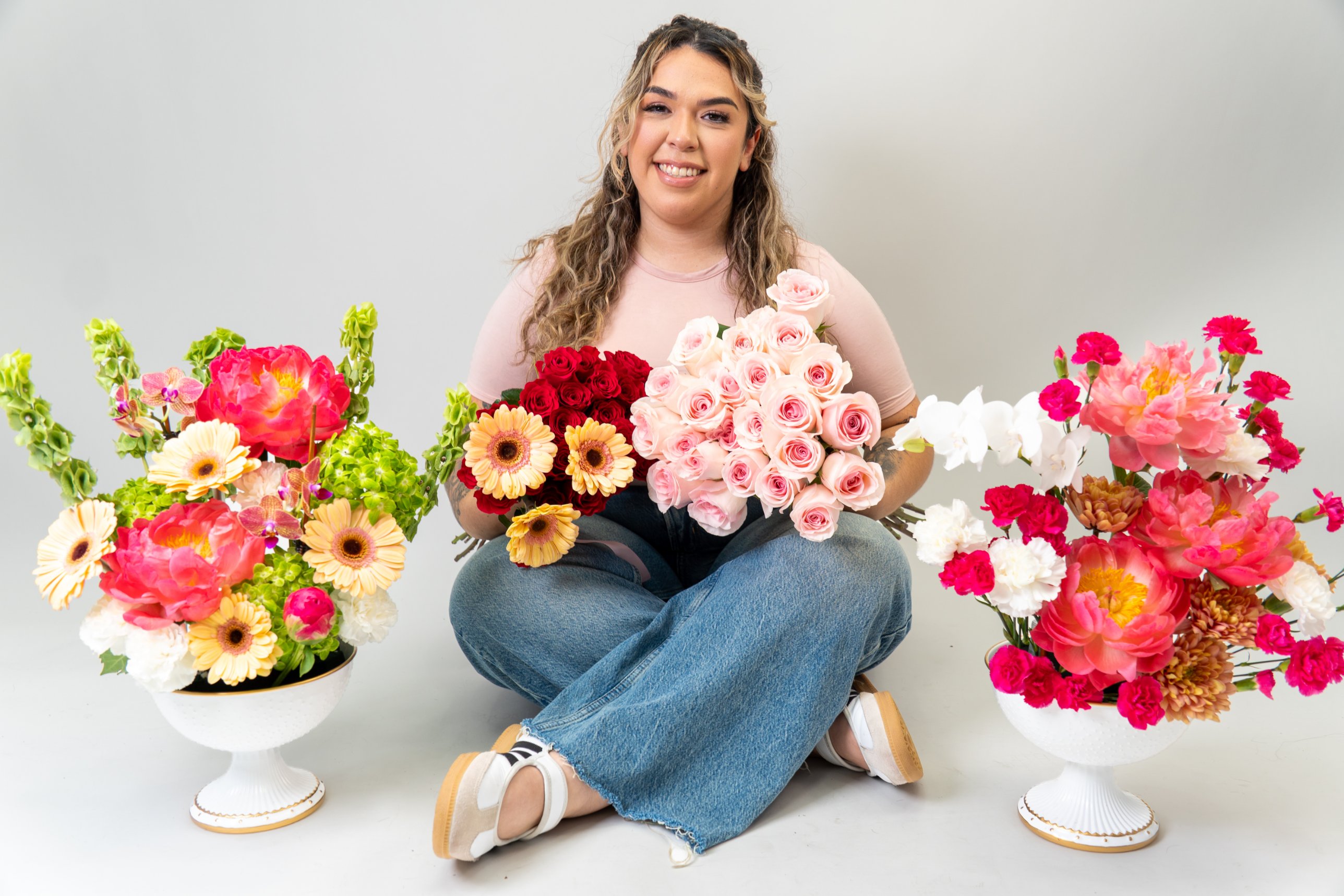 Seated in the studio between two flower arrangements